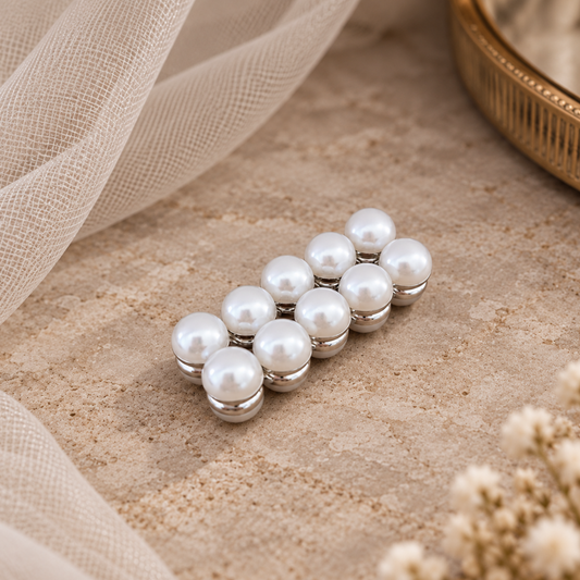 A cluster of eight white faux-pearl Veil Weights with silver-toned metal caps, arranged on a textured beige fabric with soft cream tulle and dried flowers.